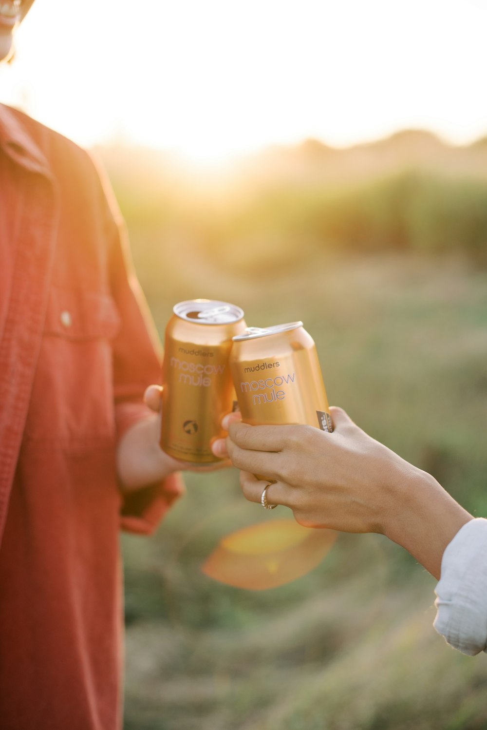 a man and a woman holding two cans of beer