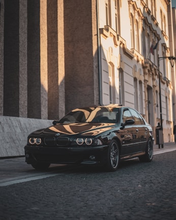 A shiny black sedan parked near a traditional Moroccan riad entrance with colorful tiles.