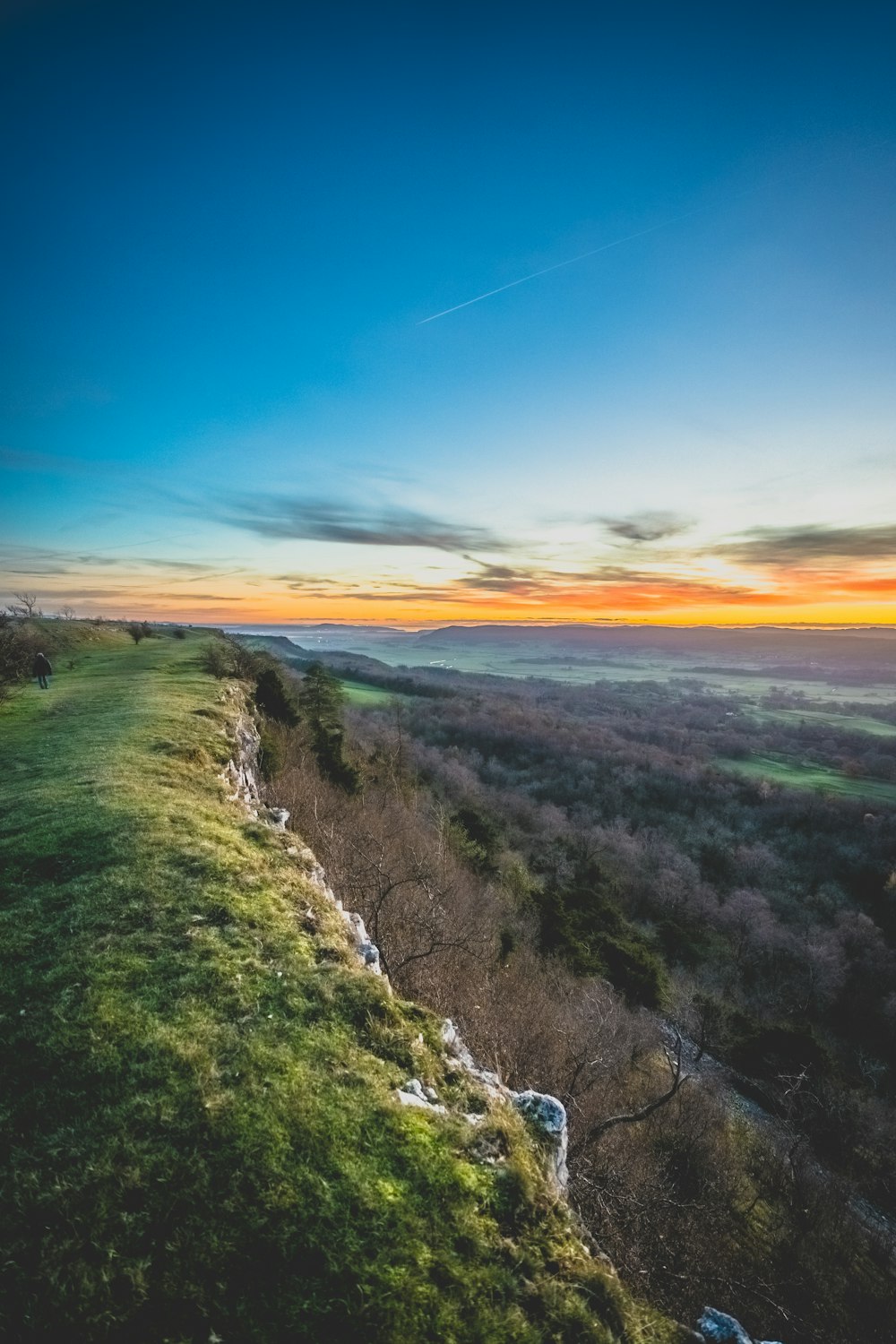 a view of a grassy hill with a sunset in the background