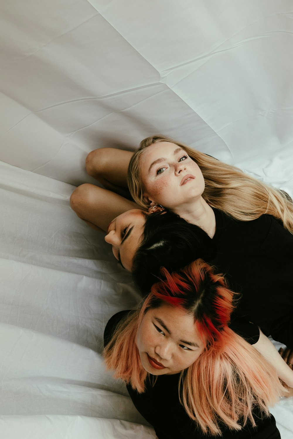 two women laying on a bed with white sheets