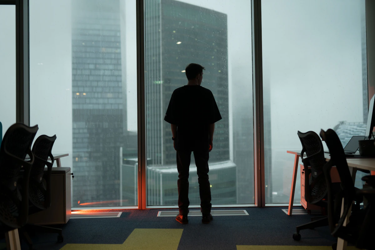Mann steht in einem Büro und schaut aus dem Fenster