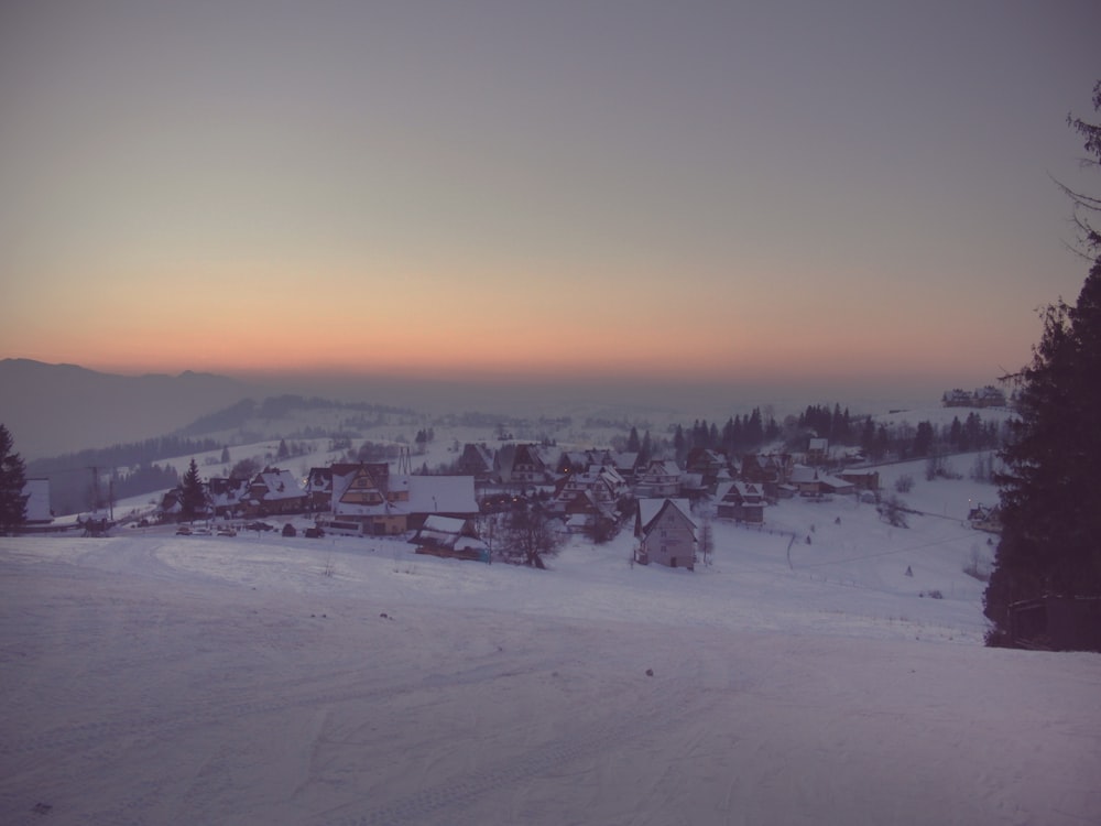 a snow covered ski slope with a village in the distance