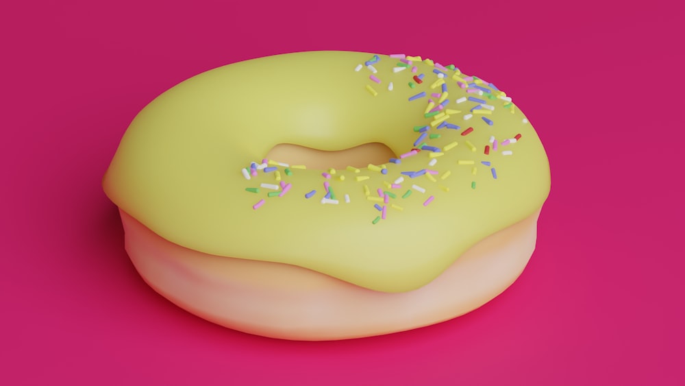 a yellow donut with sprinkles on a pink background