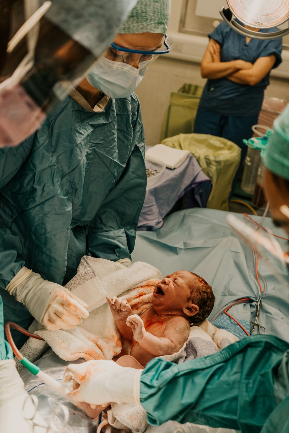 um bebê em uma cama de hospital com pessoal médico ao seu redor