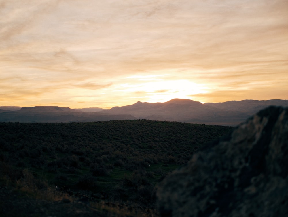 the sun is setting over the mountains in the distance