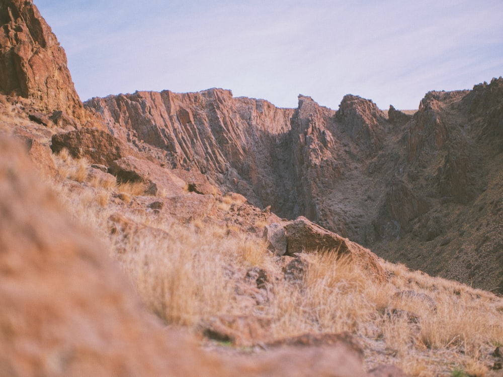 a view of a rocky mountain side with dry grass