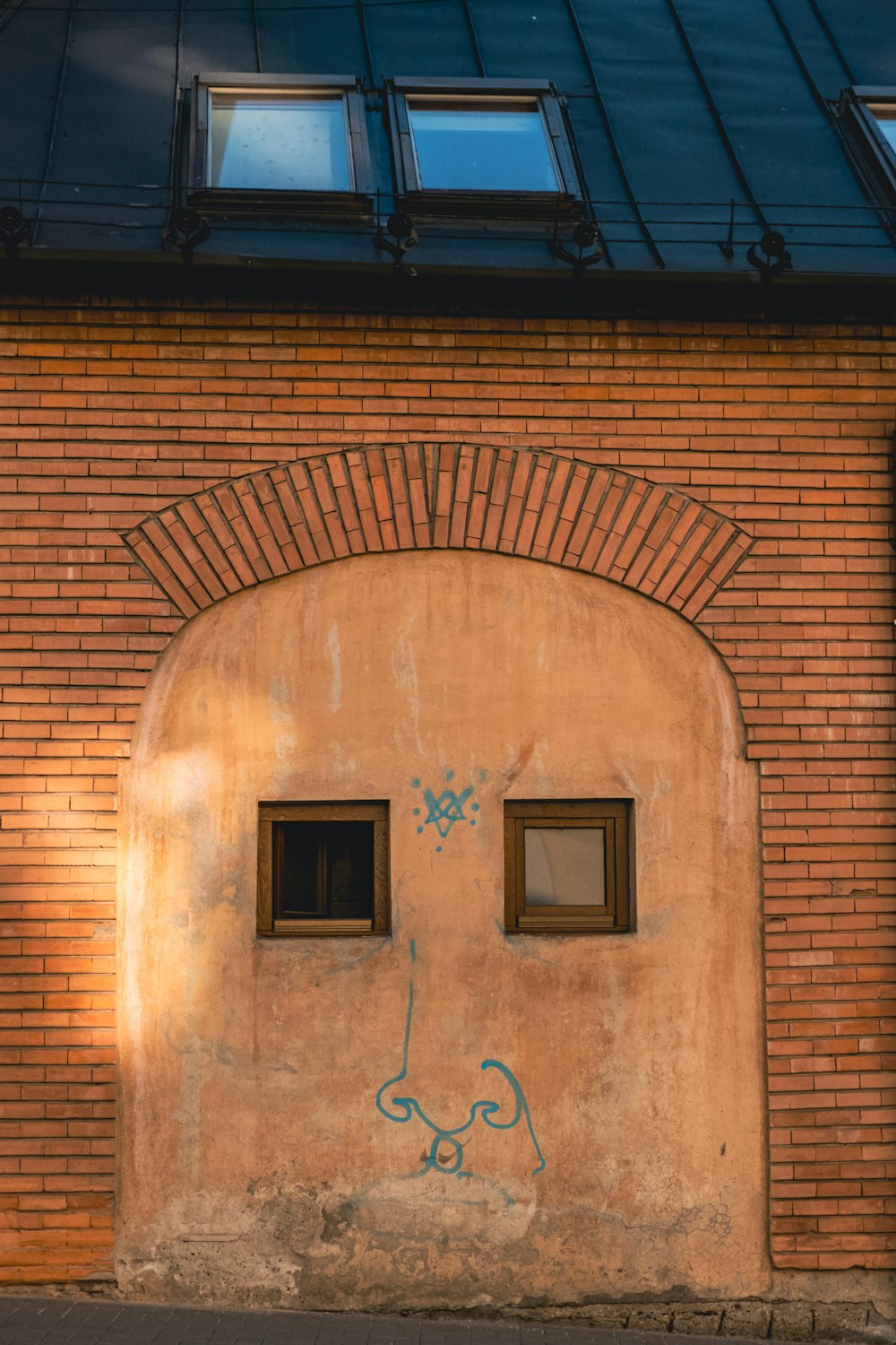 a brick building with two windows and graffiti on it