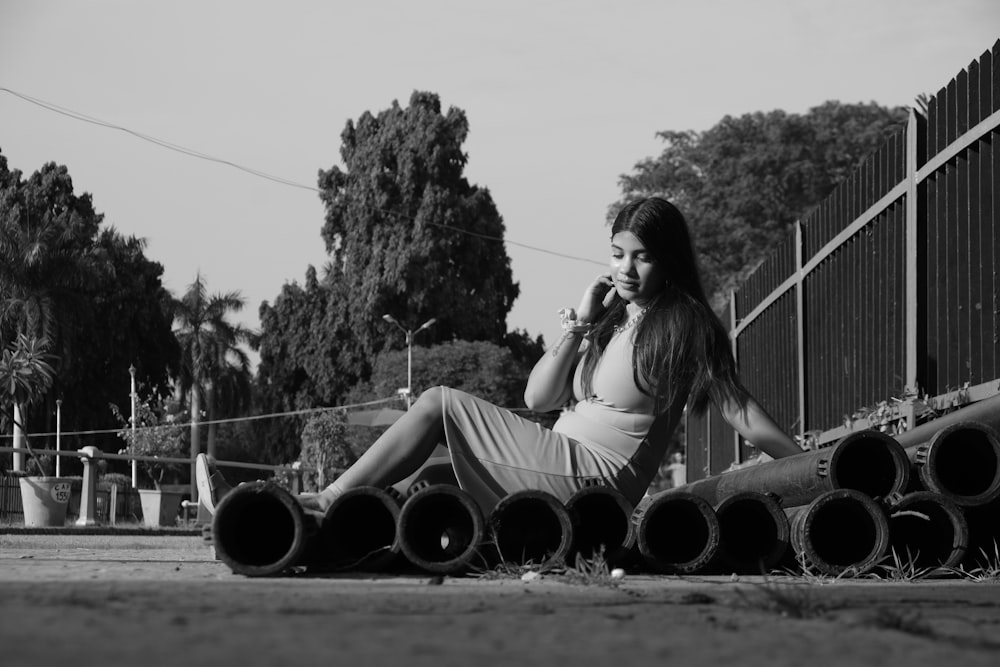 a woman sitting on the ground talking on a cell phone