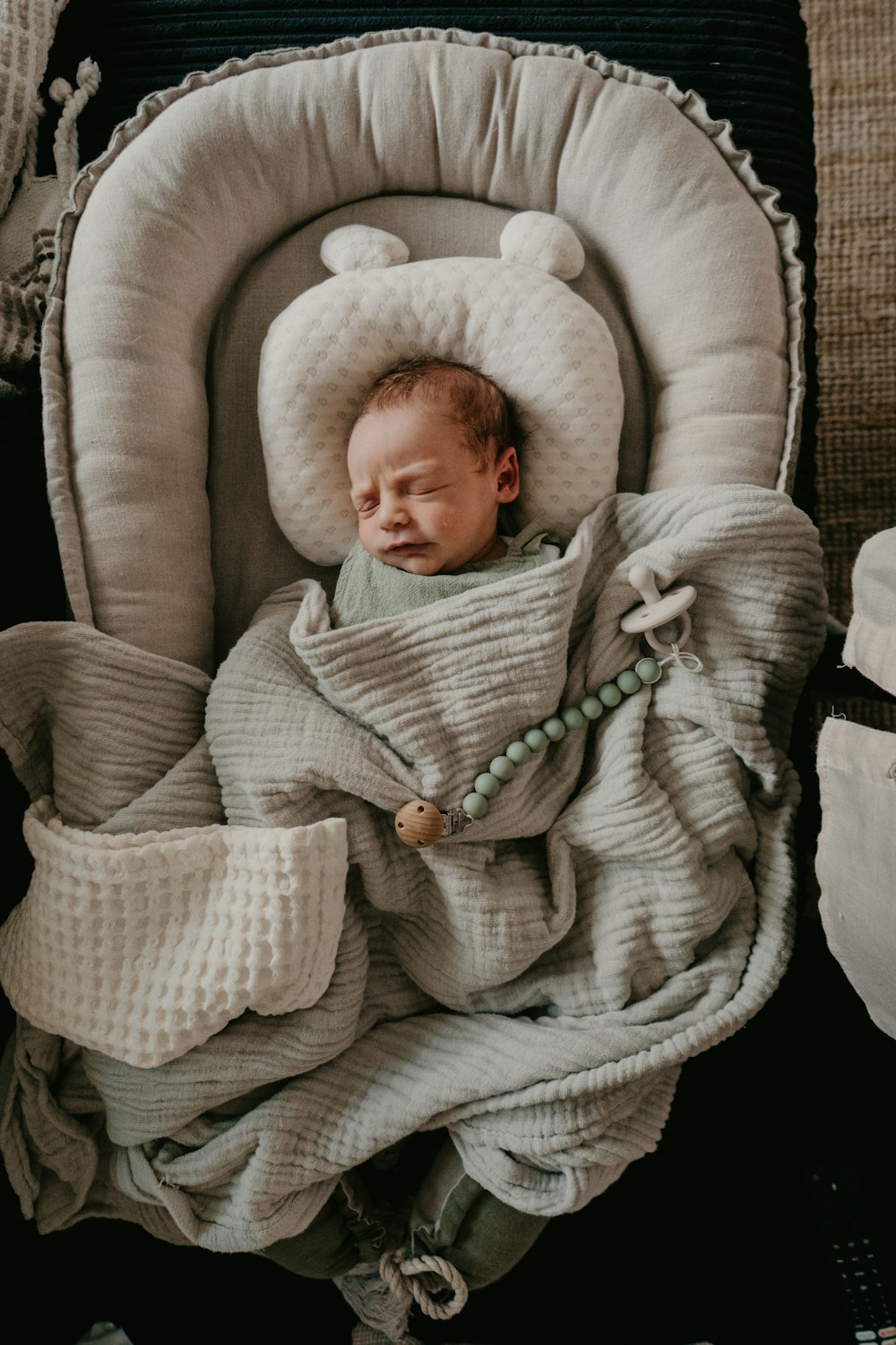 a baby wrapped in a blanket sleeping in a chair