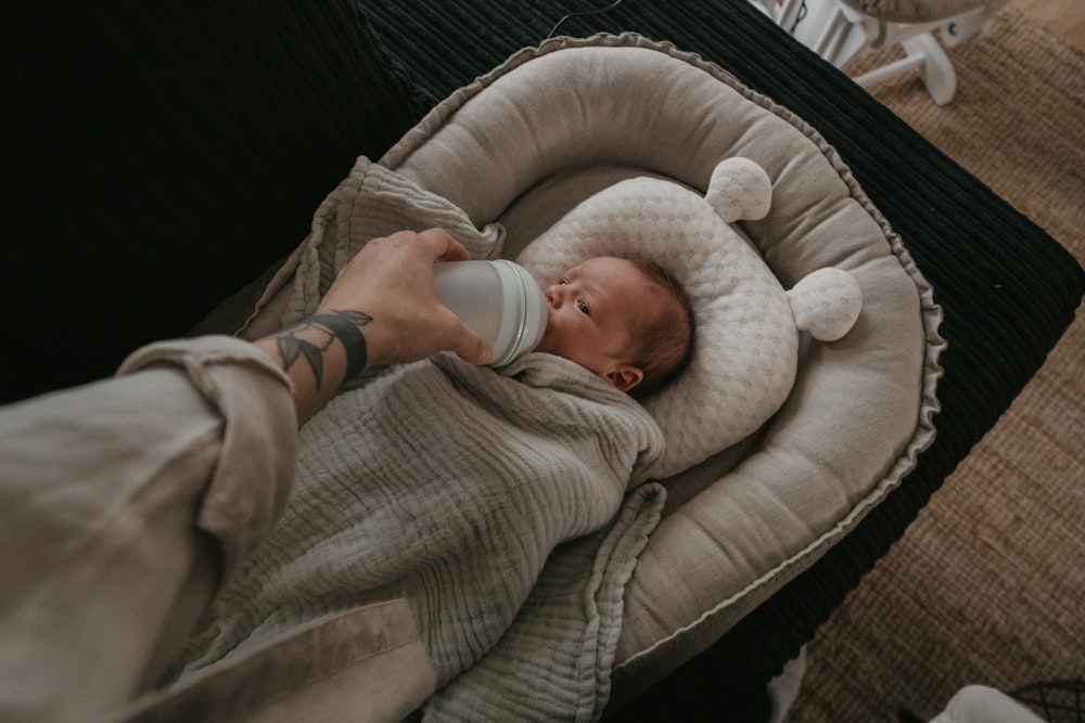 a person holding a bottle in their hand while holding a baby