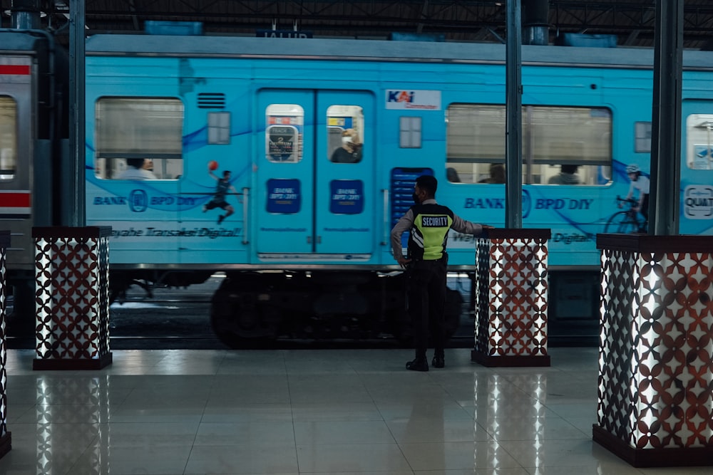 Un hombre parado frente a un tren en una estación de tren