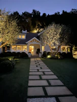 A twilight exterior shot of a charming home with warm lights glowing through the windows.