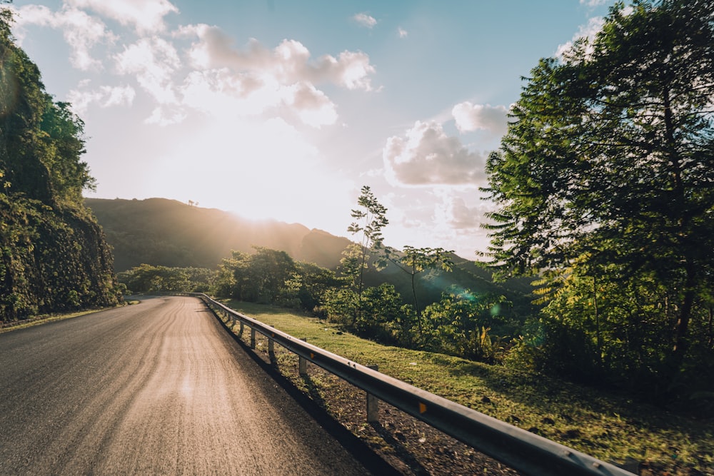 the sun shines through the clouds over a road