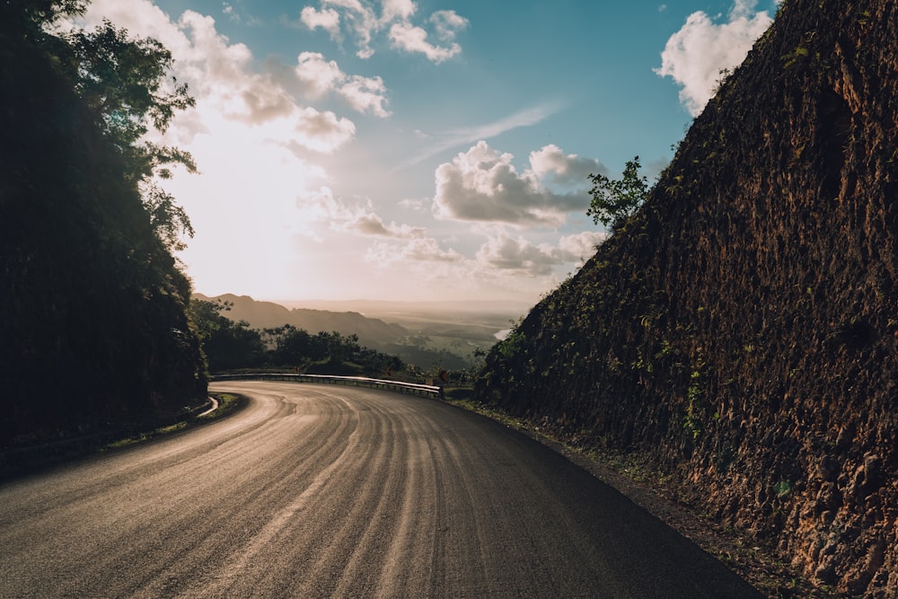 the sun shines through the clouds over a mountain road