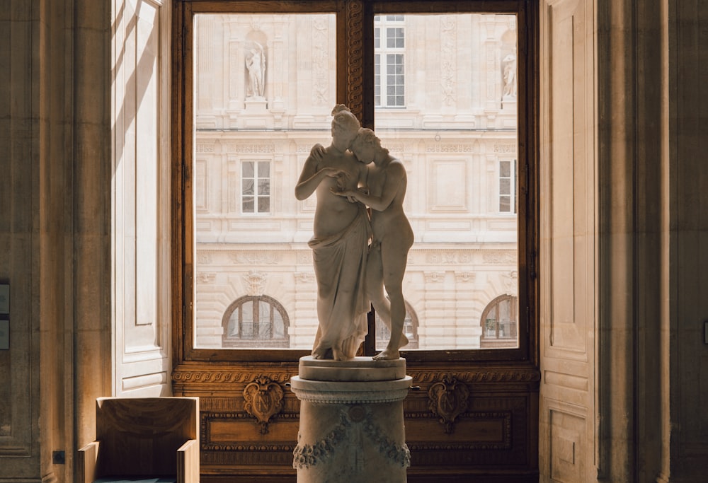 une statue d’un homme et d’une femme devant une fenêtre