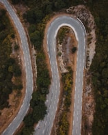 An aerial view of a winding road through lush green hills.