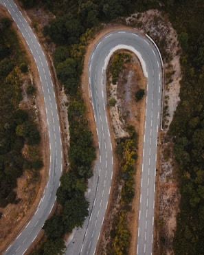An aerial view of a winding road through lush green hills.