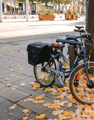 a blue bike parked next to a tree on a sidewalk