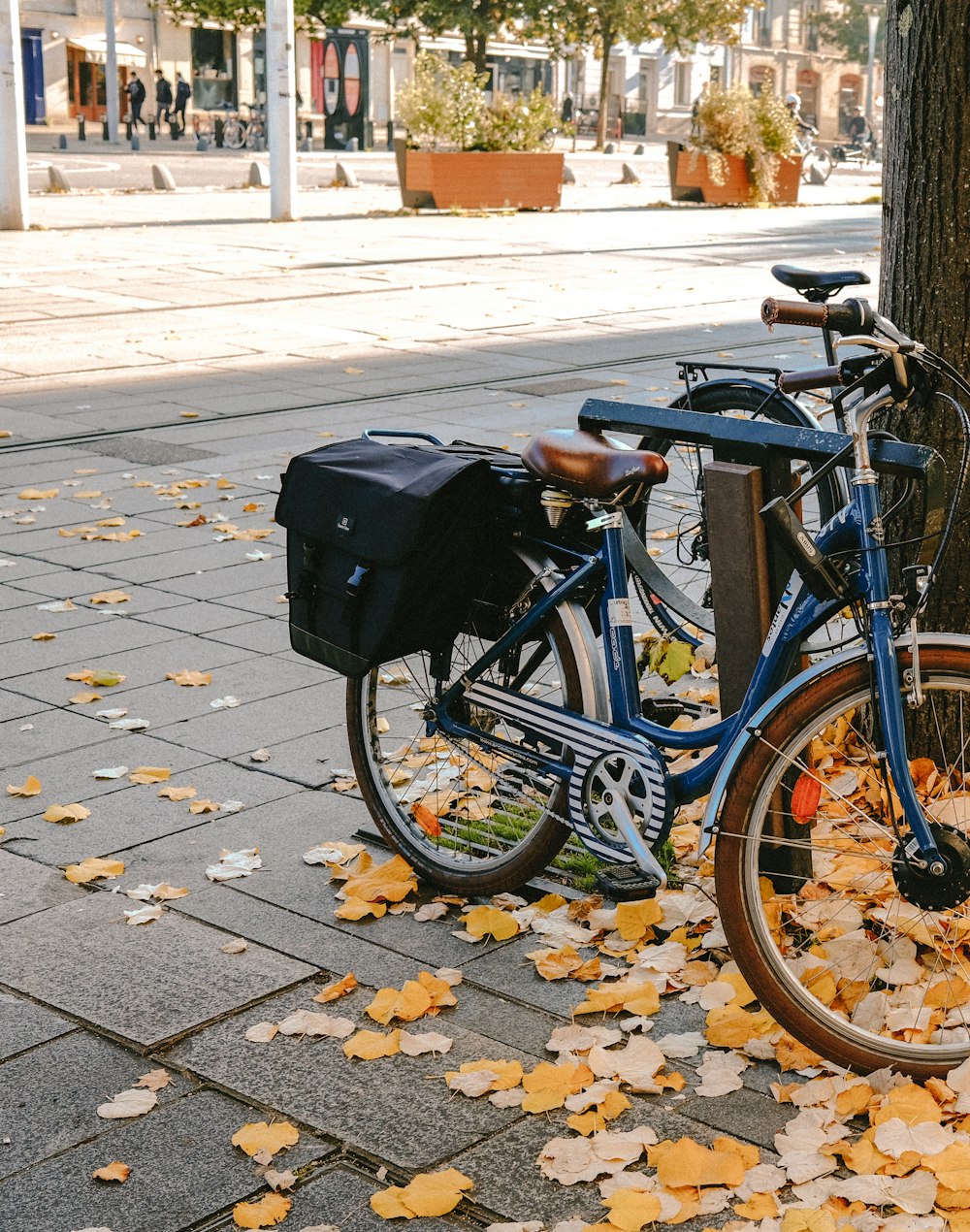 a blue bike parked next to a tree on a sidewalk