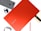 A red Samsung Chromebook laptop is positioned centrally with its brand name visible. Surrounding it are various tech accessories, including a smartphone with a fabric cover, a pair of wireless earbuds, a smart watch, and a stylus pen.