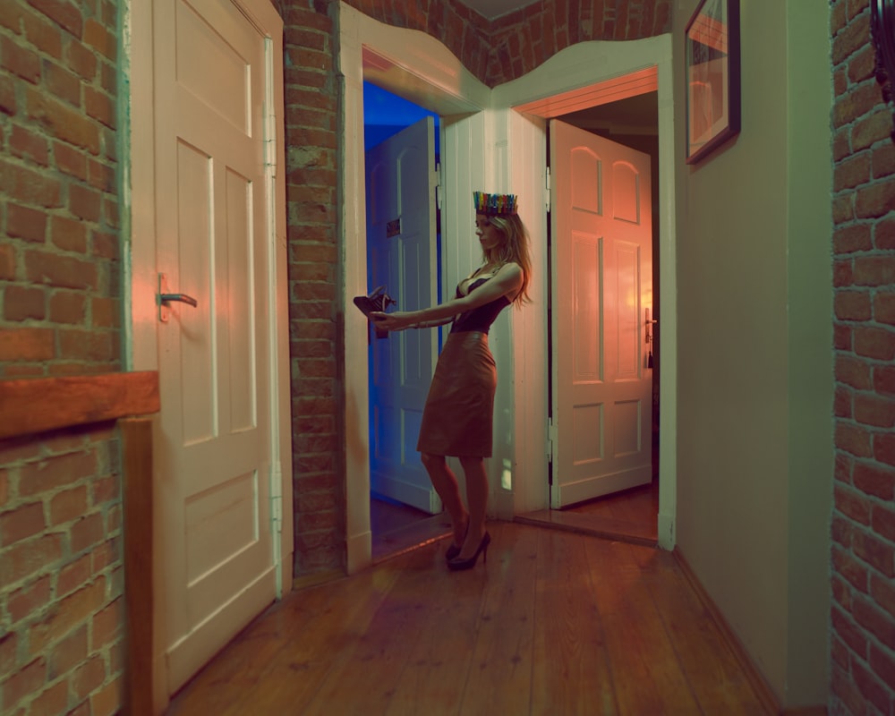 uma mulher em pé em um corredor com uma porta aberta