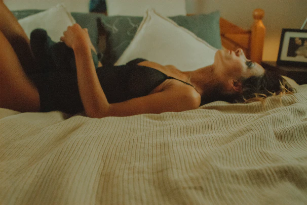 Cozy nightwear ensemble with a woman gracefully lounging in elegant sleep dresses in muted nude tones, inside a minimalistic bedroom