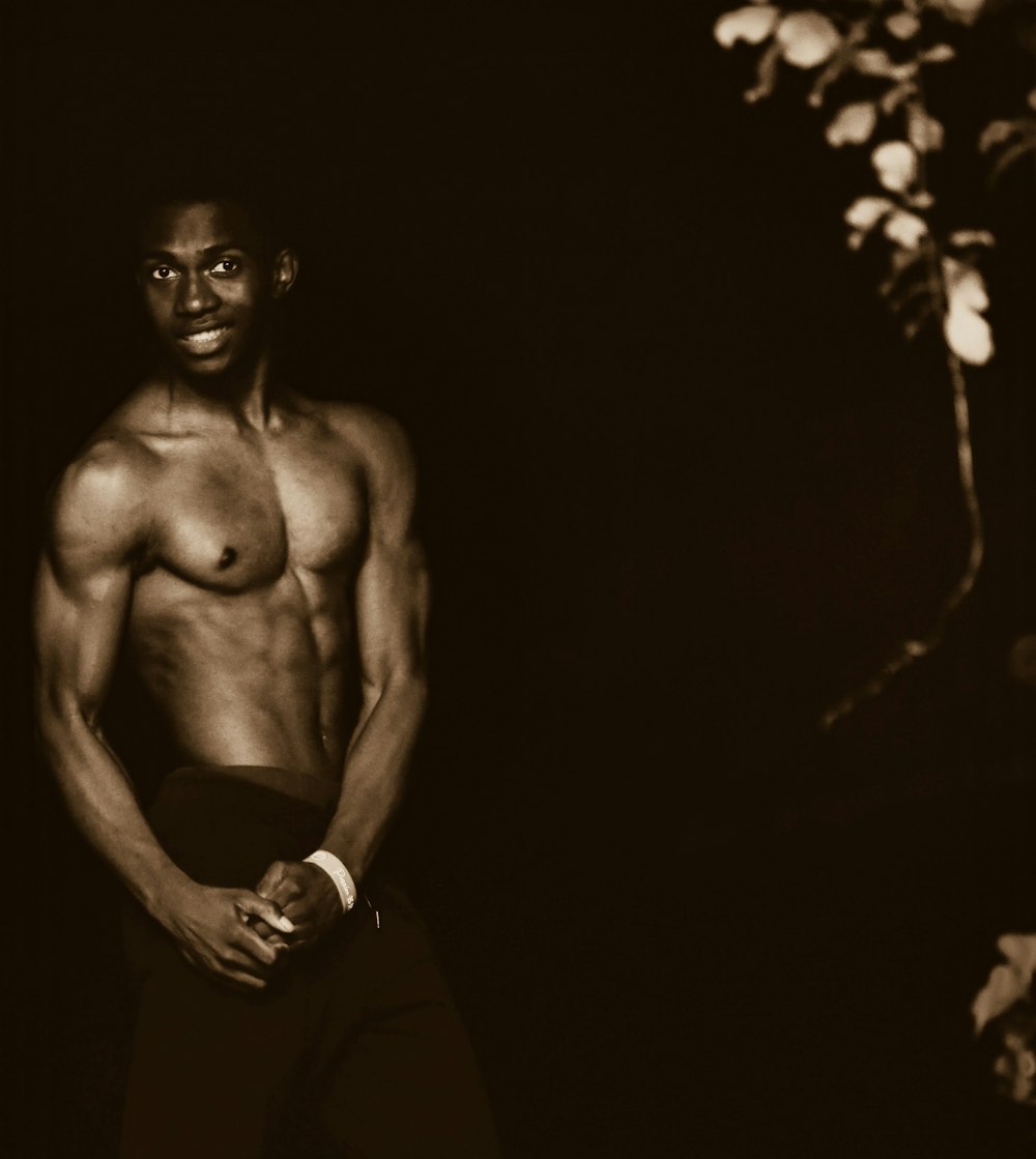 a shirtless man standing in a dark room