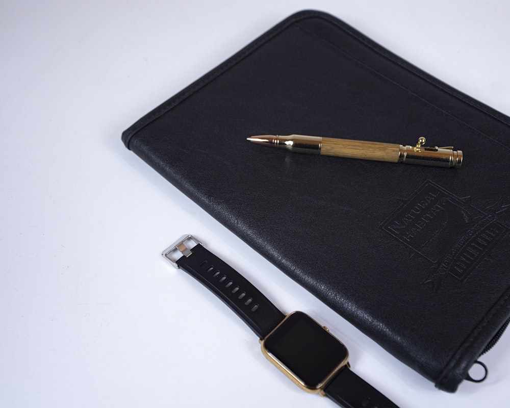 a pen and a watch sitting on top of a black case