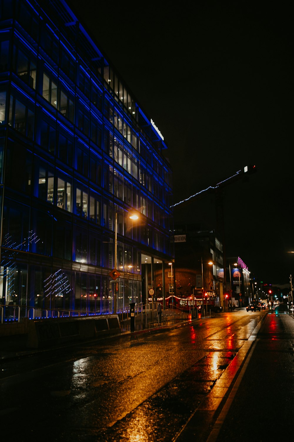 a city street at night with a building lit up with blue lights
