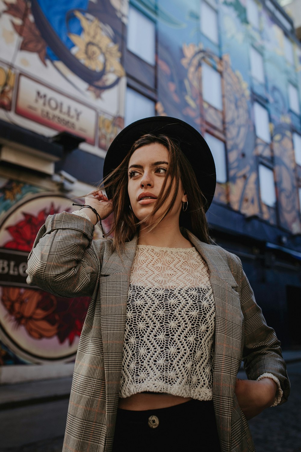 a woman wearing a hat and jacket standing in front of a building