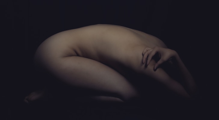 a nude woman is bending over in the dark