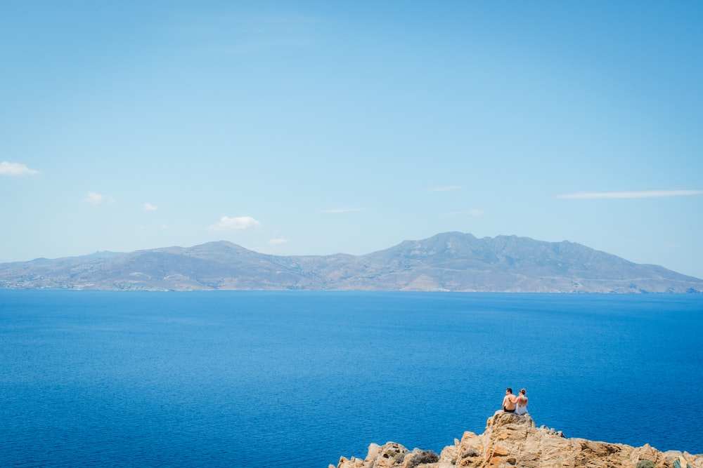 a couple of people sitting on top of a cliff