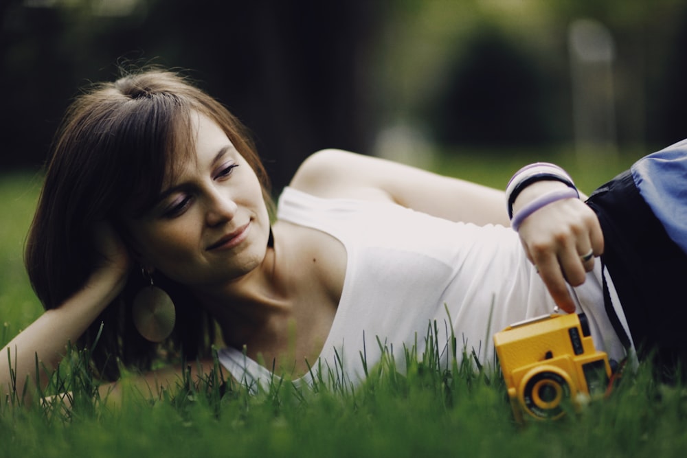 a woman laying in the grass with a camera