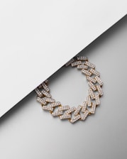 A close-up of a stylish chain necklace laid on a textured surface.
