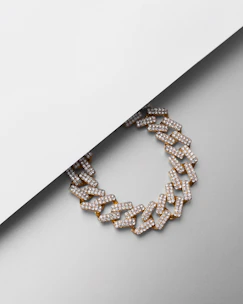 Close-up of a sleek men's gold chain resting on a black velvet surface, highlighting its modern design.