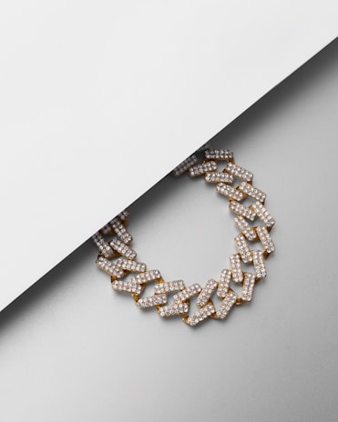 A close-up of a stylish chain necklace laid on a textured surface.