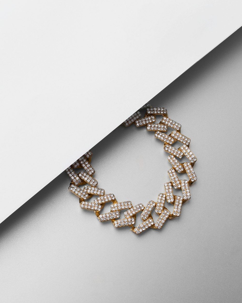 a gold and diamond bracelet on a white surface