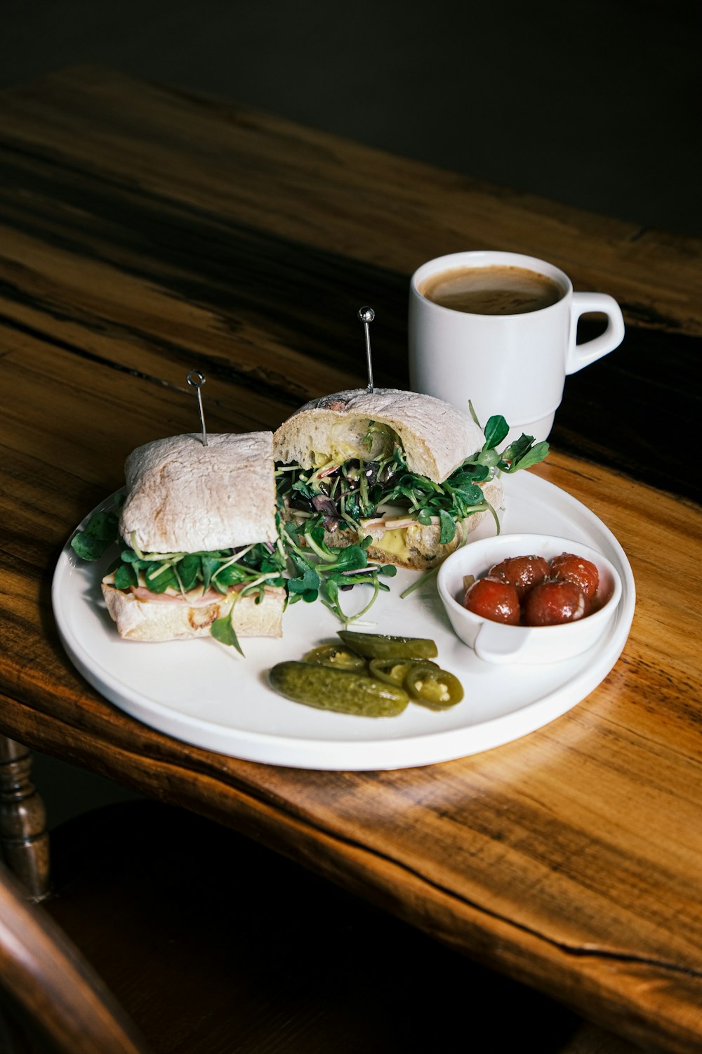 a white plate topped with a sandwich and a cup of coffee