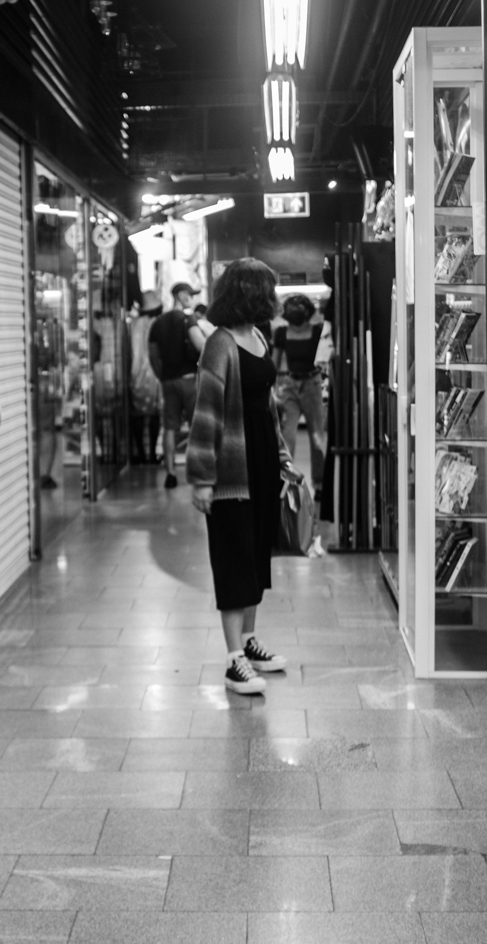 a black and white photo of a woman standing in a store