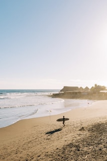 a person holding a surfboard on a beach