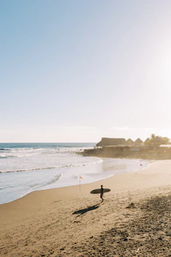 a person holding a surfboard on a beach