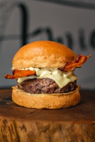 Close-up of a sizzling smash burger with melted cheese, crispy edges on a dark rustic background.