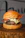 Close-up of a juicy Casa Llena burger with melted cheese and fresh toppings on a rustic wooden table.