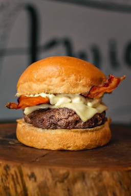 Close-up of a hickory smoked burger with melted cheese, crispy bacon, and fresh lettuce on a toasted bun.