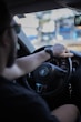 a man driving a car with his hand on the steering wheel