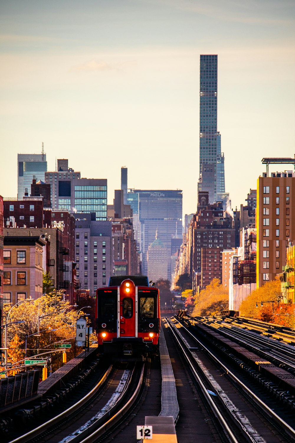 a red train traveling down train tracks next to tall buildings