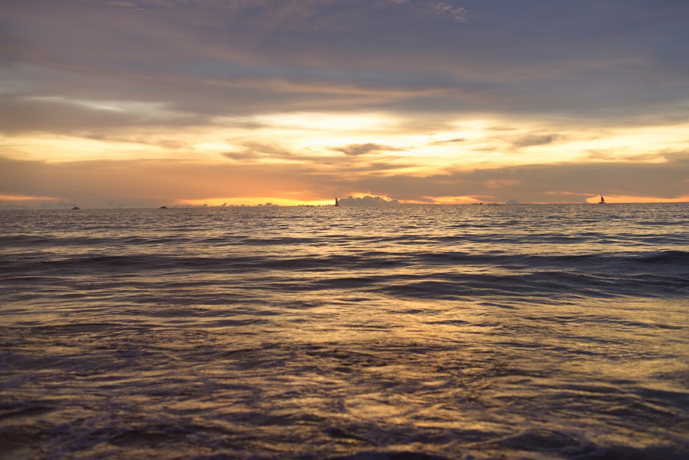 Die Sonne geht über dem Meer unter, mit Booten in der Ferne