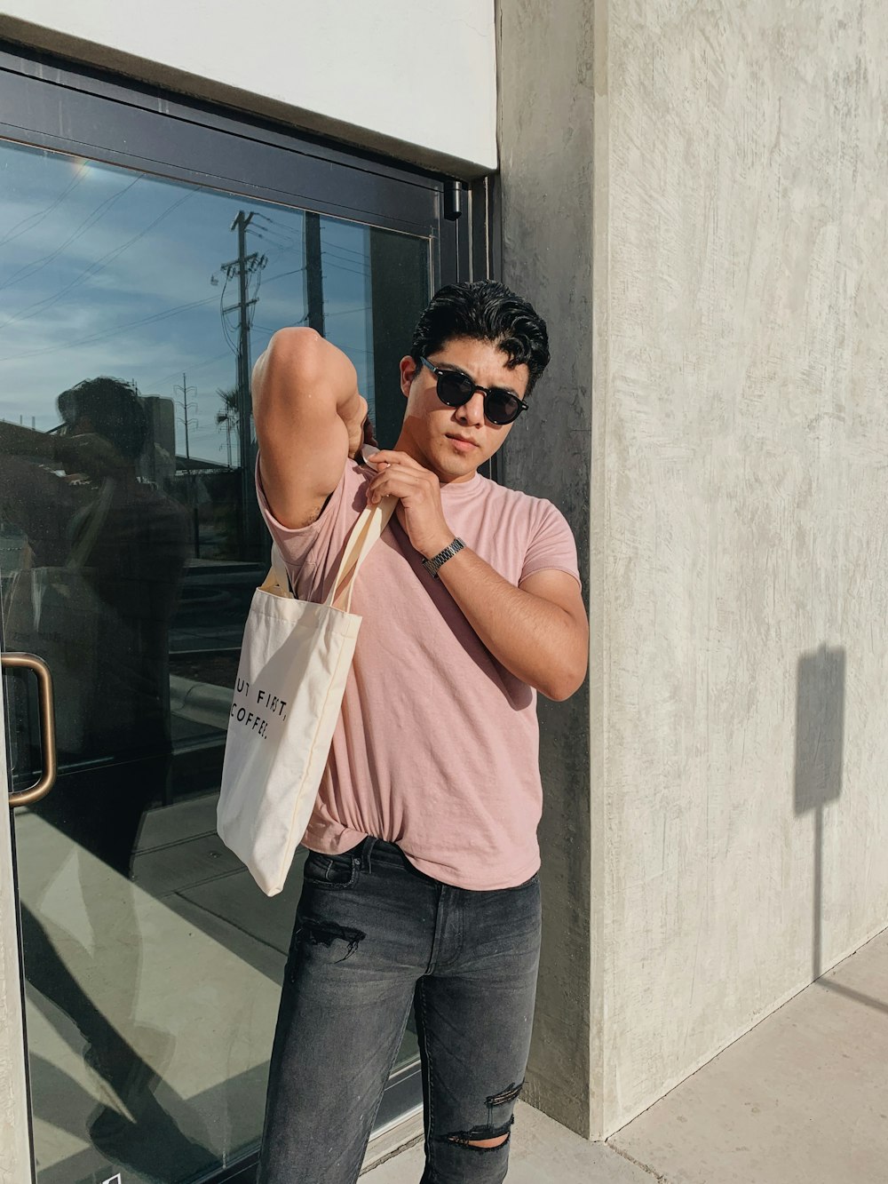 a man in sunglasses and a pink shirt is holding a bag