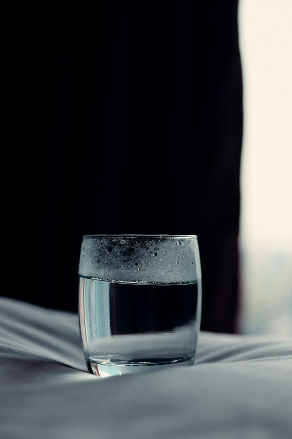 a glass of water sitting on top of a bed