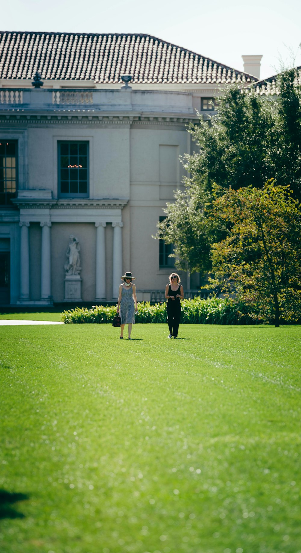 a couple of people walking across a lush green field